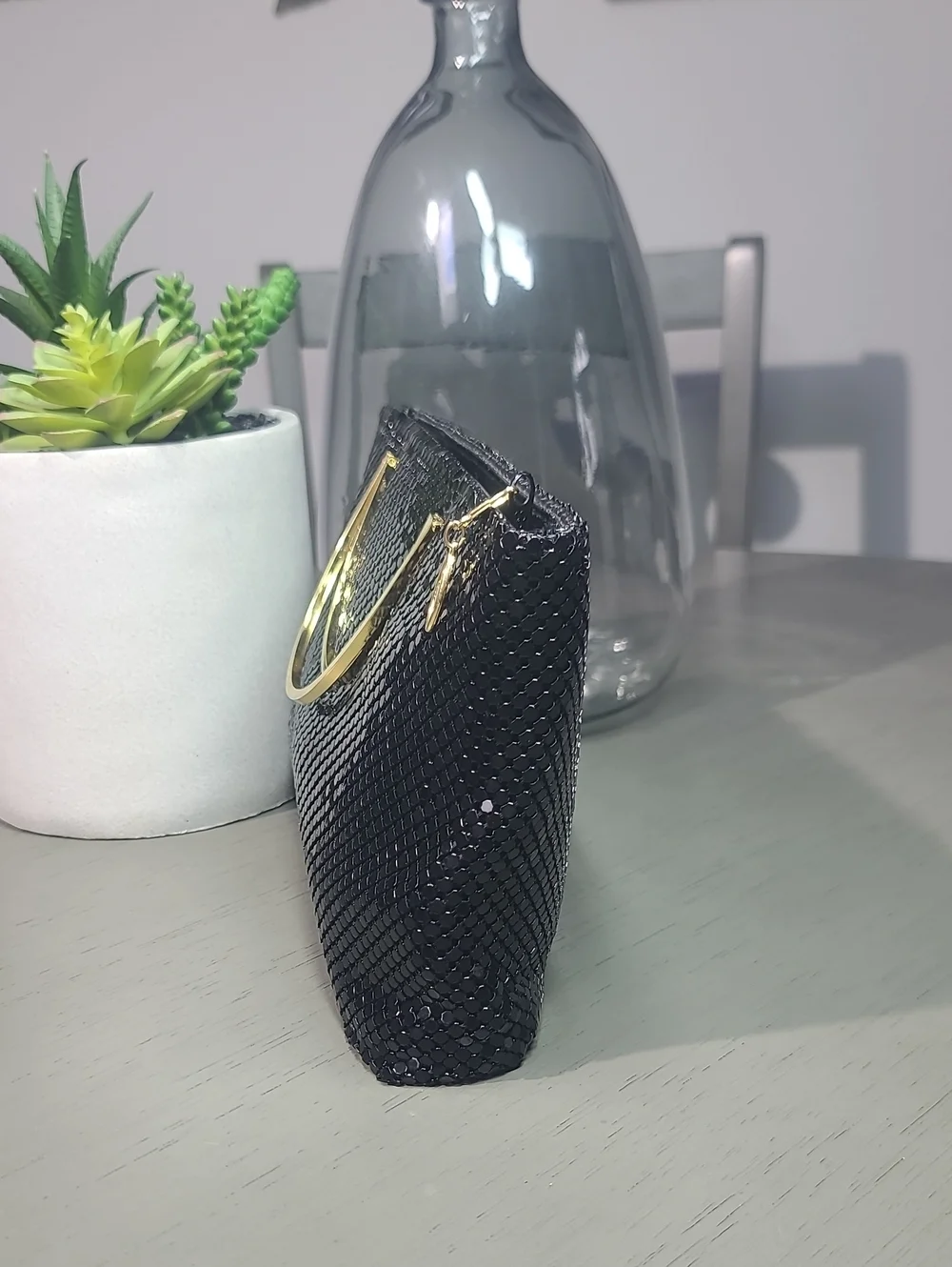 Sophisticated black mesh metal  clutch with a polished gold-tone oval handle.